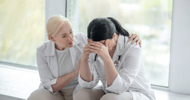 Female physician comforting another female physician